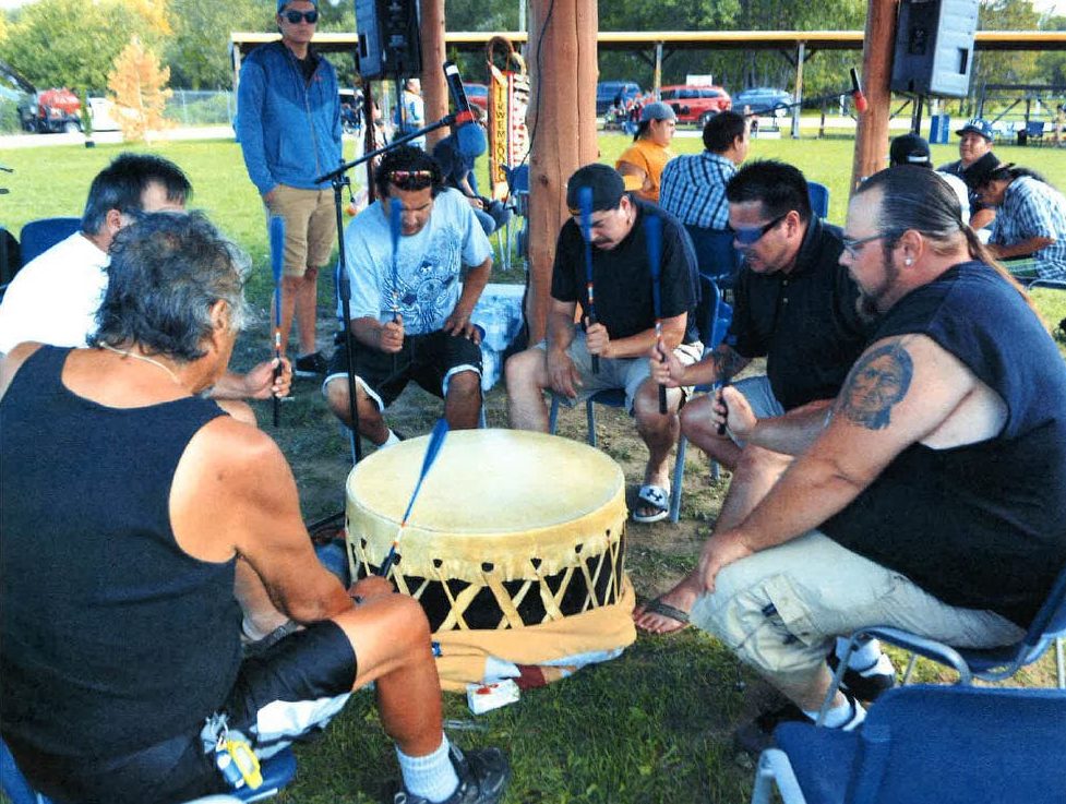 A group of men sitting around a drum